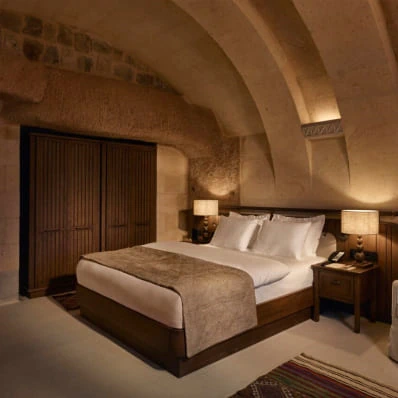 Cave room with wood-headboard bed at Argos in Cappadocia